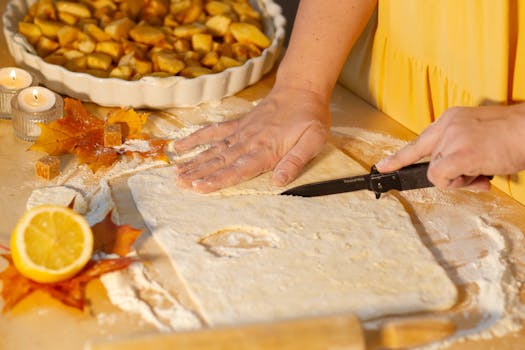 Préparation de la pâte à tarte pour une tarte aux pommes, avec des pommes coupées en morceaux en arrière-plan.