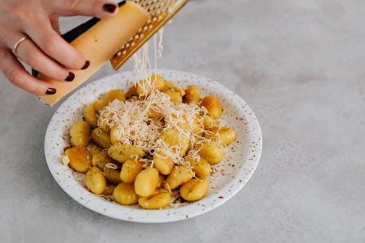 Gnocchis aux vitelottes garnis de fromage râpé sur une assiette blanche.