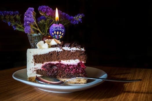 Partie de gâteau praliné-chocolat avec une bougie d'anniversaire, décorée de fleurs et posée sur une assiette.
