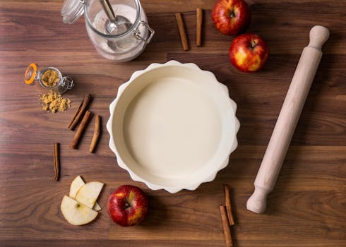 Ingrédients pour une tarte aux pommes : moule à tarte, pommes, épices, rouleau à pâtisserie et tranches de pomme.