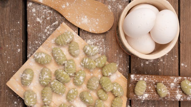 Gnocchis aux vitelottes sur une planche en bois, avec des œufs et de la farine éparpillée sur la table.